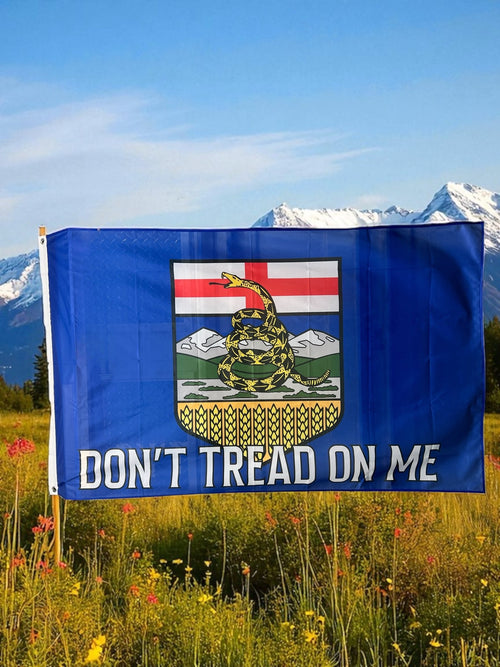 Alberta Flag with 'Don't Tread on Me' text in a field with mountains in the background